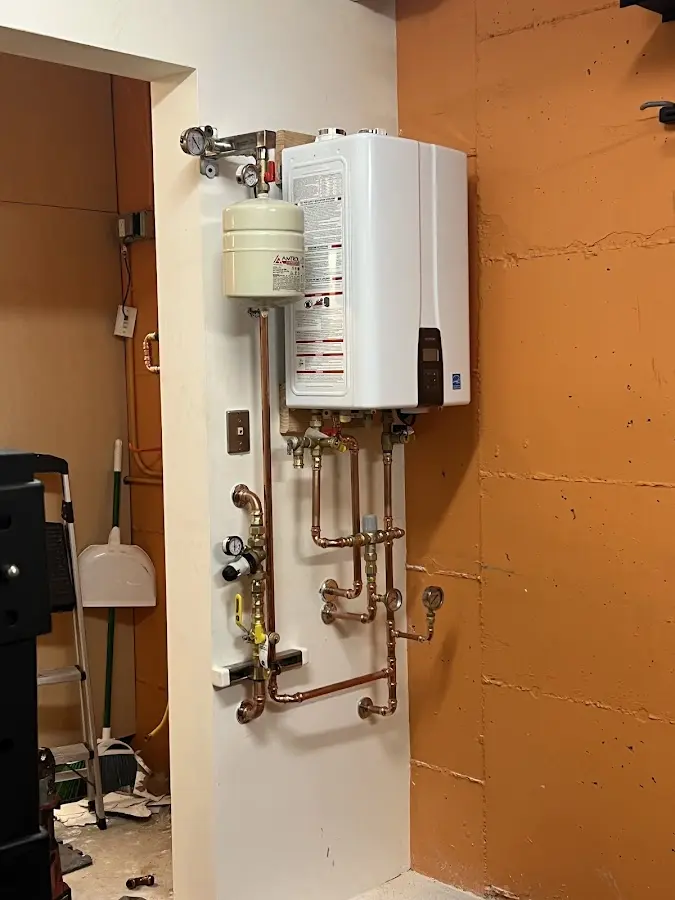 Plumbing technician inspecting water heater connections in Big Lake